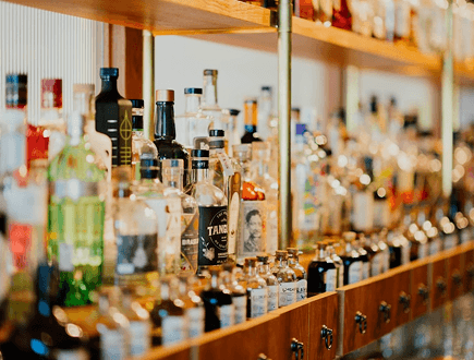 Spirits bottles lined up along a bar shelf